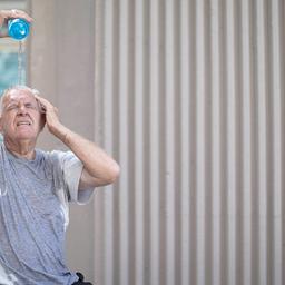 Ein älterer Mann gießt sich bei Sommerhitze Wasser auf den Kopf. (Quelle: dpa)