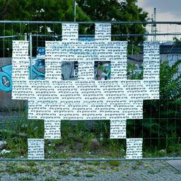 Eine Figur des Spiels "Space Invaders" auf einem Berliner Bauzaun