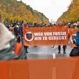 Umwelt-Aktivisten haben die Straße des 17. Juni besetzt und halten ein Plakat mit der Aufschrift "Weg von Fossil hin zu gerecht". (Quelle: dpa/Paul Zinken)