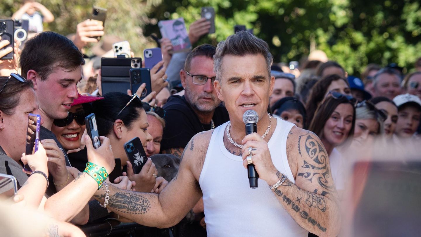 Robbie Williams schüttelt Hände in Melbourne, Australien. Er trägt ein weißes Achselhemd