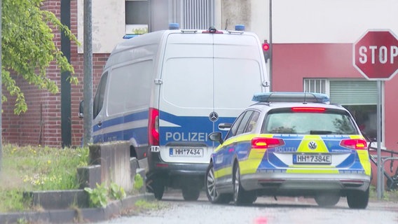 Zwei Polizeifahrzeuge fahren auf ein Grundstück. © Screenshot 