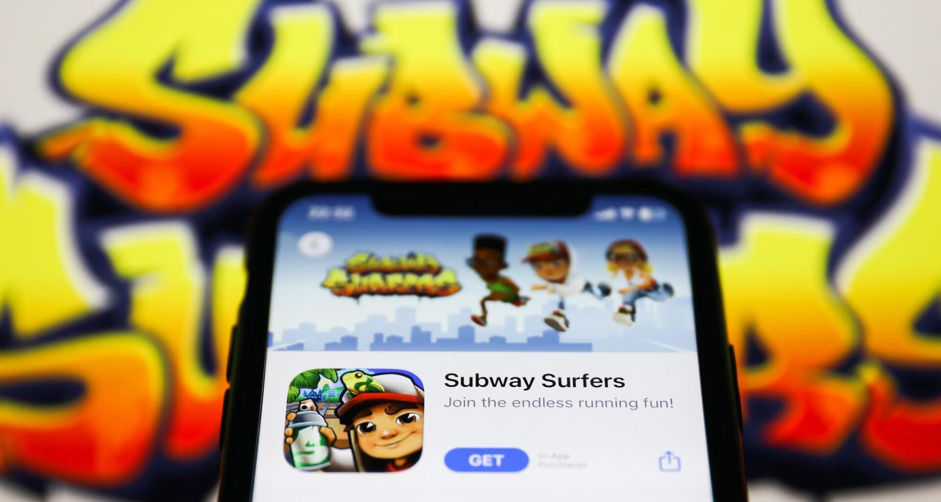 Ein Handy zeigt die App "Subway Surfers" im Hintergrund ist der Schriftzug des Spiels zu sehen.