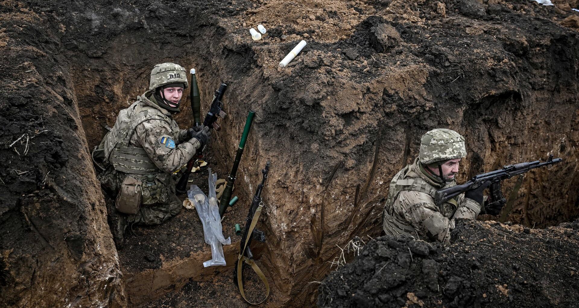 Zwei Soldaten der 110. Territorialverteidigungsbrigade befinden sich in einem Schützengraben in der Region Saporischschja im Südosten der Ukraine. Sie tragen Tarnuniformen, Helme und Schutzwesten.