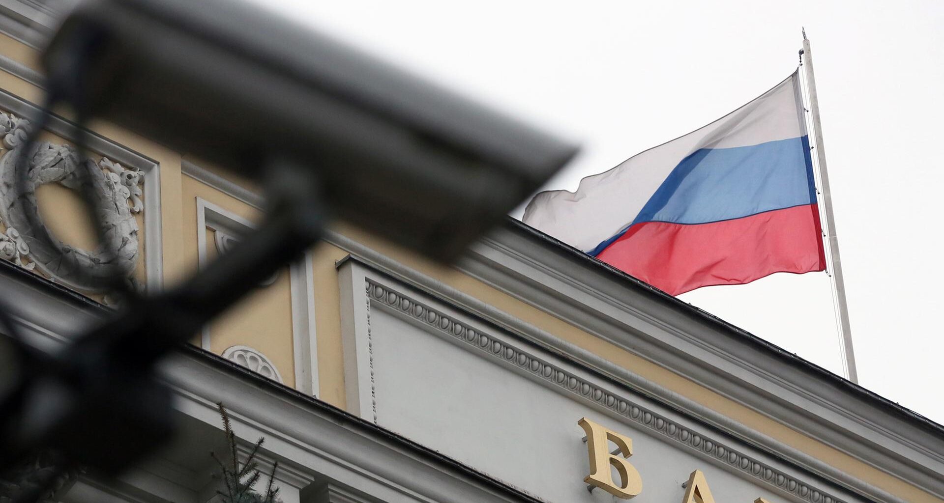 Auf der russischen Zentralbank in Moskau weht eine Russland-Fahne, davor ist eine Überwachungskamera zu sehen