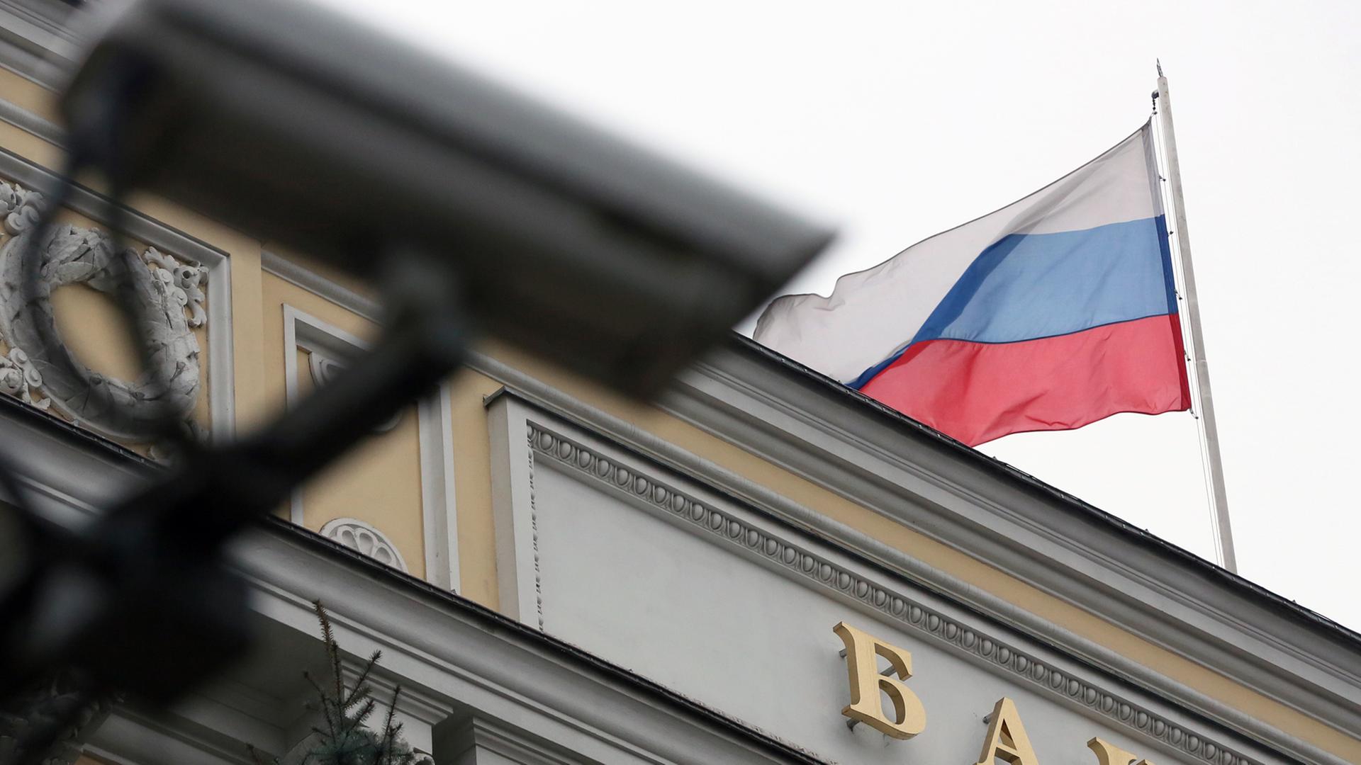 Auf der russischen Zentralbank in Moskau weht eine Russland-Fahne, davor ist eine Überwachungskamera zu sehen