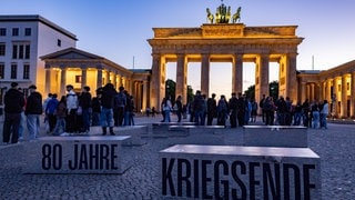 Menschen gedenken 80 Jahre Kriegsende am Brandenburger Tor (Foto: IMAGO, IMAGO / A. Friedrichs) Menschen gedenken 80 Jahre Kriegsende am Brandenburger Tor