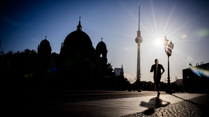 Ein Jogger rennt am frühen Morgen des 30.06.2025 vor dem Berliner Fernsehturm und dem Dom. (Quelle: dpa-Bildfunk/Christoph Soeder)
