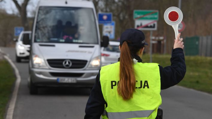 Archivbild: Eine polnische Polizistin winkt vor dem Grenzübergang in Polen an der polnisch-deutschen Grenze einen Reisebus zur Kontrolle raus. (Quelle: dpa/Sauer)