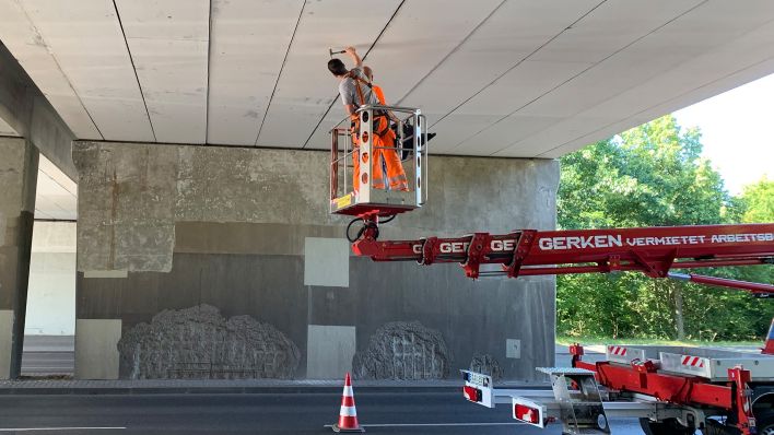 Rico Thumeyer sucht mit dem Hammer nach Hohlstellen und anderen Schäden, die im Beton entstanden sein könnten. (Quelle: rbb24/Sebastian Schöbel)