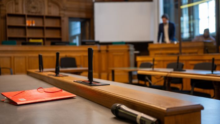 Eine rote Aktenmappe liegt auf einem Tisch in einem Verhandlungssaal im Kriminalgericht Moabit.