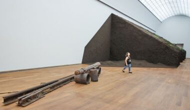 Eine Frau läuft am 08.07.2025 bei einer Vorbesichtigung an dem Kunstwerk von Delcy Morelos im Hamburger Bahnhof vorbei - im Vordergrund ist ein Kunstwerk von Joseph Beuys zu sehen (Quelle: imago images/Funke Foto Services)