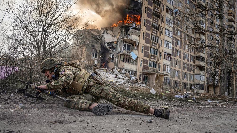 Russischer Angriffskrieg: Verzweifelte Verteidigung Awdijiwkas im März 2023: Ein Haus wird von Granaten getroffen, ein ukrainischer Soldat geht in Deckung. Knapp ein Jahr später nehmen russische Truppen die Stadt in der Oblast Donezk ein.