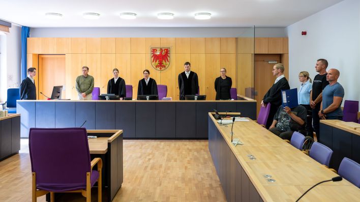 Grit Burzer (M), Vorsitzende Richterin, eröffnet den Prozess nach der Messerattacke von Casekow. Der heute 28-jährige Angeklagte (4.v.r) soll im Januar 2025 eine Frau und ihren Sohn getötet haben. (Quelle: dpa/Stache)