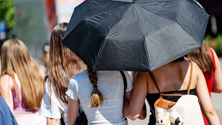Symbolbild:Menschen laufen mit Schirm bei hohen Temperaturen über den Pariser Platz vor dem Brandenburger Tor.(Quelle:picture alliance/dpa/F.Sommer)