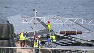 Arbeiter montieren auf dem Cottbuser Ostsee die Solarmodule der Photovoltaik-Anlage (Archivfoto: rbb/Screenshot)