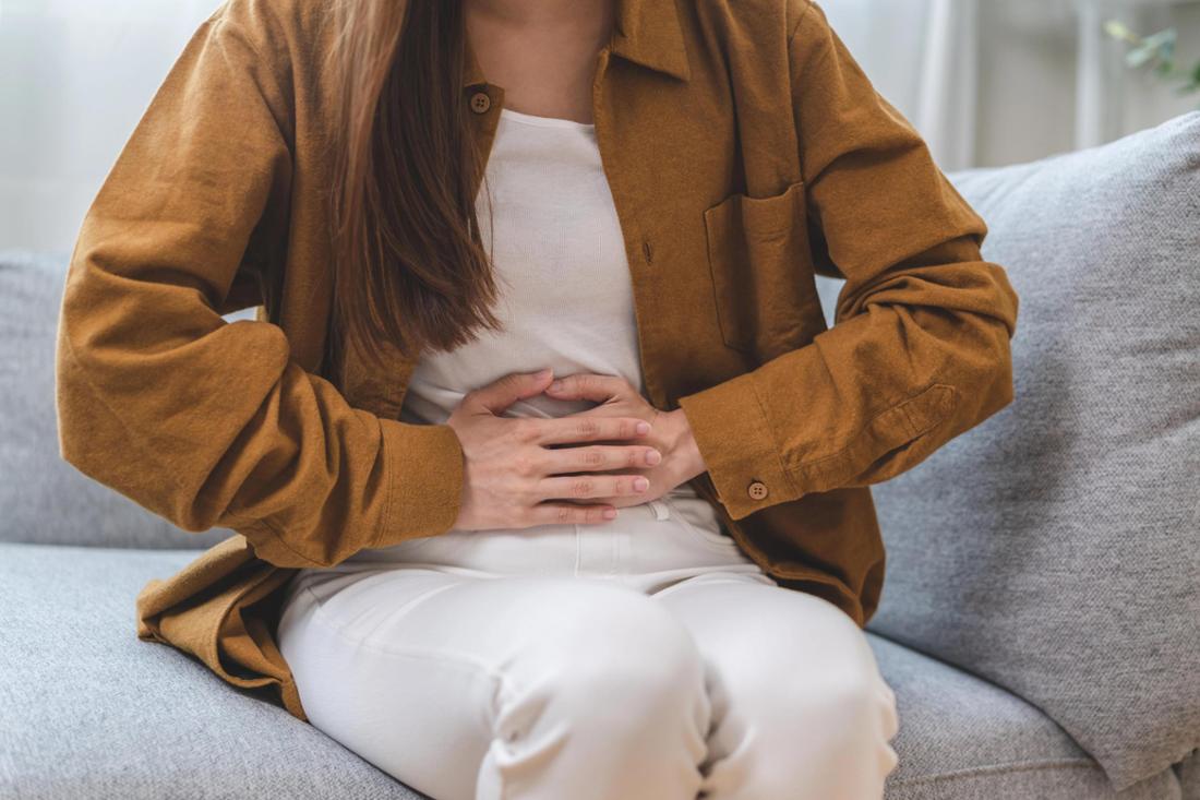 Frau hält sich Hände an Bauch.
