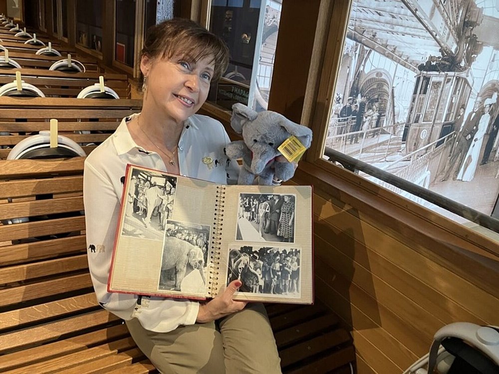 Gina Althoff, Enkelin des damaligen Zirkusdirektors, hält ein Album mit Fotos von Tuffi kurz vor und nach dem Sturz des kleinen Elefanten aus der Schwebebahn. - © Volker Danisch/dpa