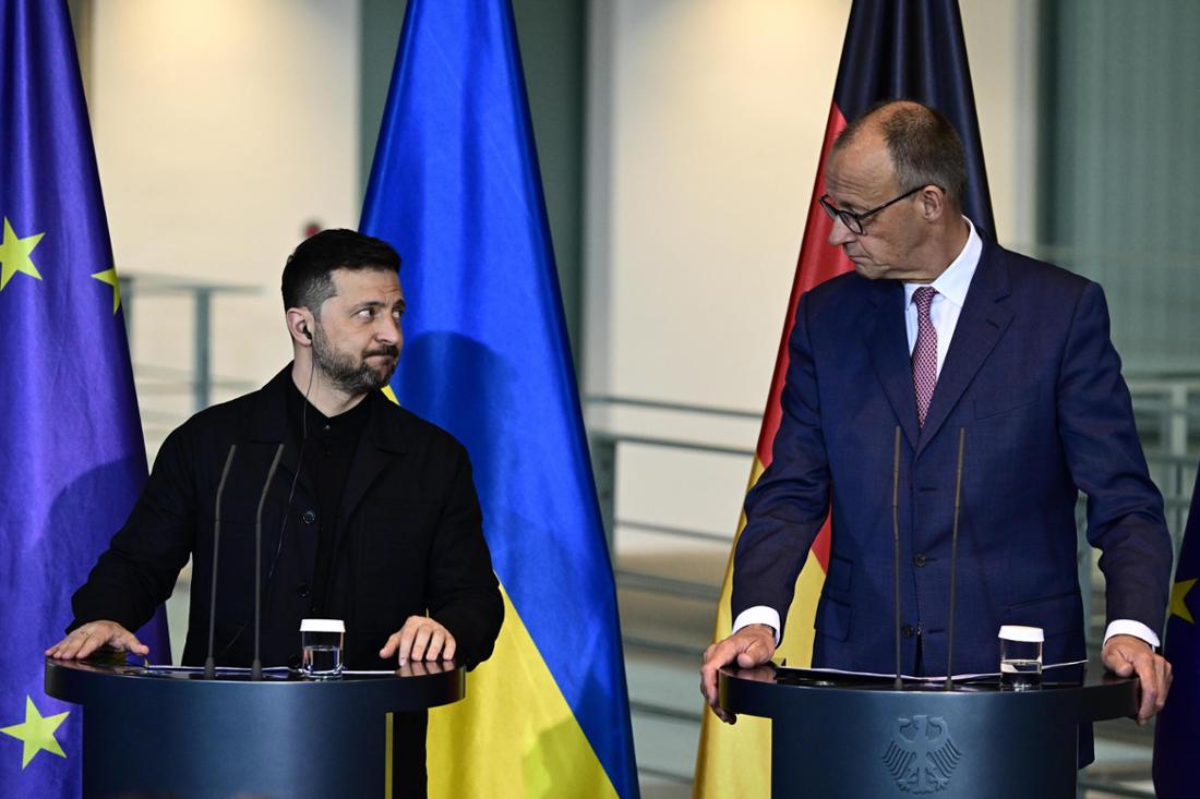 Wolodymyr Selenskyj und Friedrich Merz stehen nebeneinander und blicken sich an. 
