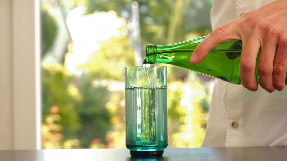 Mensch gießt sich ein Glas Wasser ein