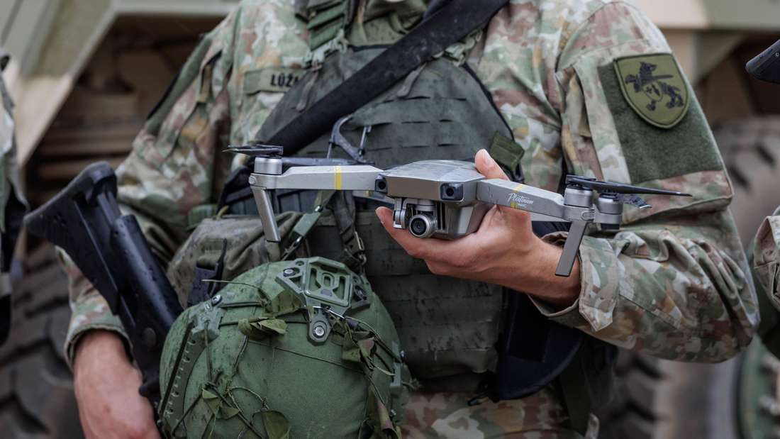 Ein Dronenpilot der litauischen Armee haelt eine Aufklärungsdrohne vor den Körper.