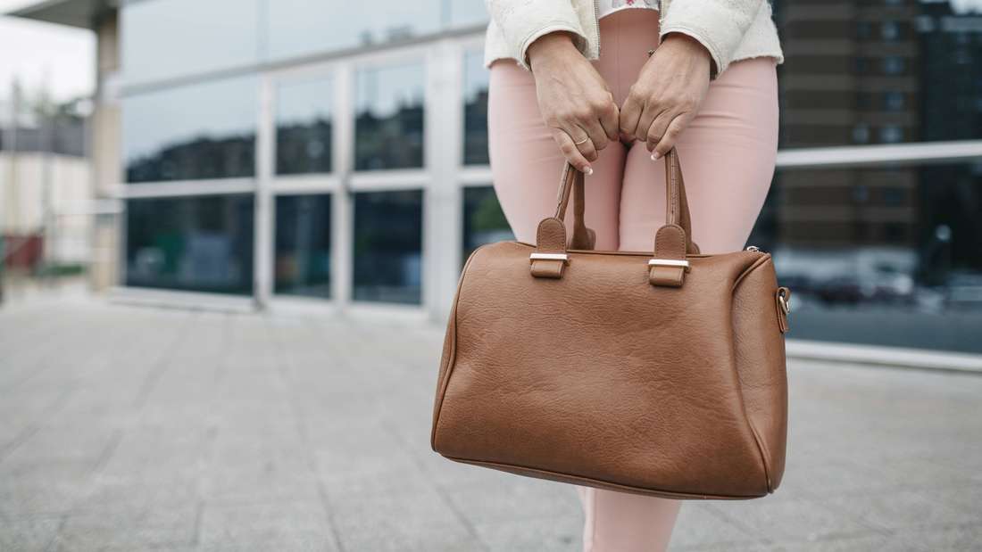 Frau hält Handtasche vor Bürogebäude