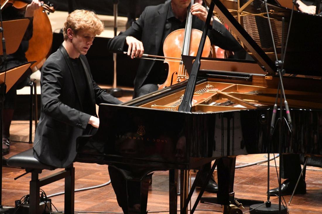 Der Pianist am Flügel, hinter ihm Orchestermusiker.
