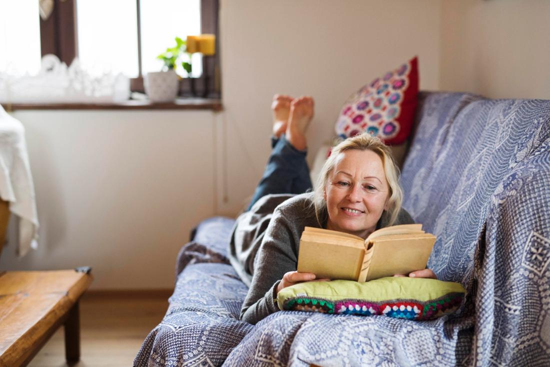 Eine Frau liest ein Buch auf einem Sofa (Symbolbild) - hier eine Leseliste mit Buchtipps herunterladen