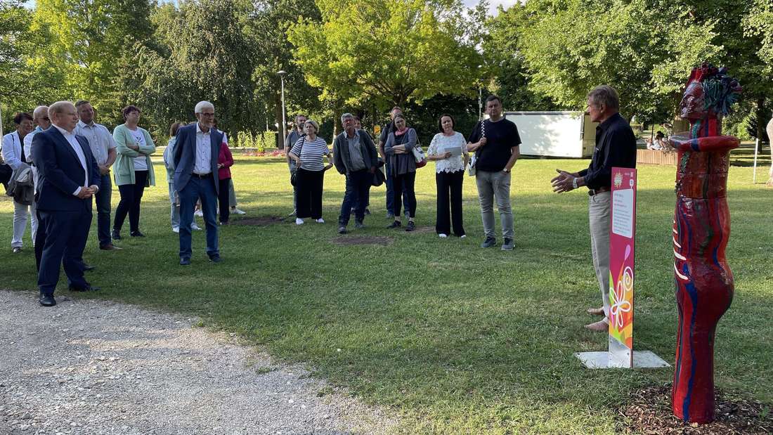 Otto Troll (r.) erläutert den Vernissage-Gästen im Neresheimer Stadtgarten sein Kunstwerk "Jenny von Mahagonny".