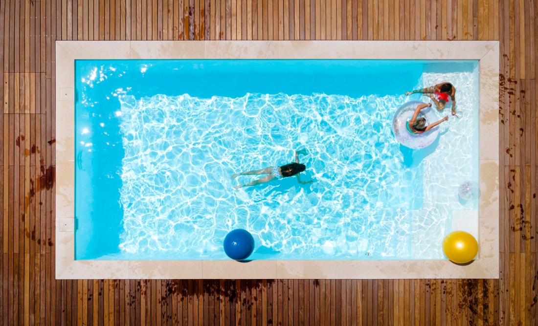 Kinder mit Mutter im Schwimmbad genießen am sonnigen Tag 