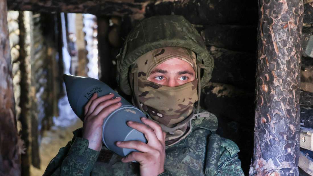 Unbekannter Artillerist der russischen Armee mit einer 122mm-Granate für eine D-30-Haubitze in einem Schützengraben