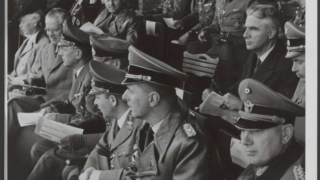 Das Schwarzweißfoto zeigt Publikum bei einer Veranstaltung, vor allem Männer in Uniform.