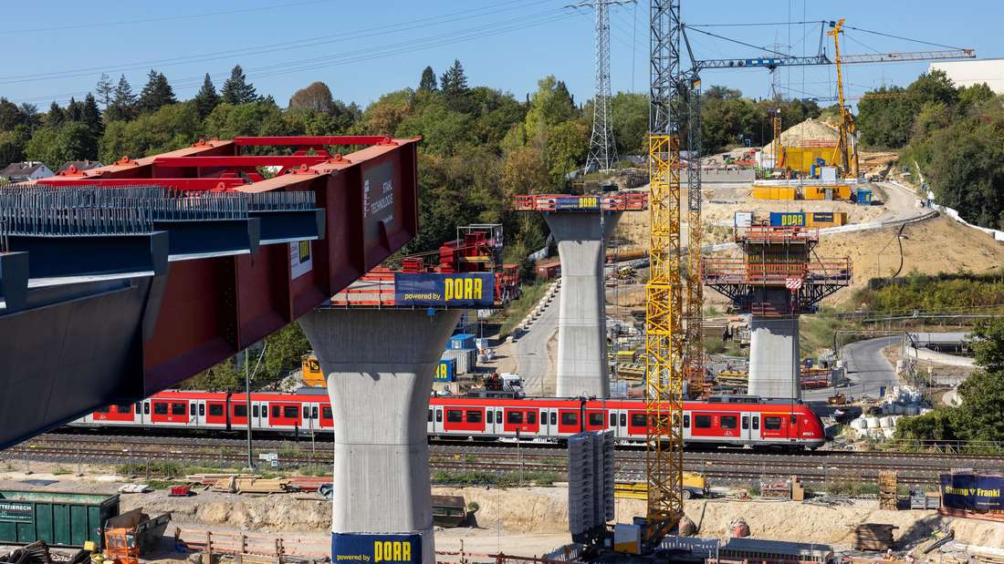 Ein Stahlteil der Brücke wird mit Hilfe eines sogenannten Schnabels über das Salzbachtal bis zum nächsten Brückenpfeiler geschoben. Unten passiert gerade eine S-Bahn die Baustelle.
