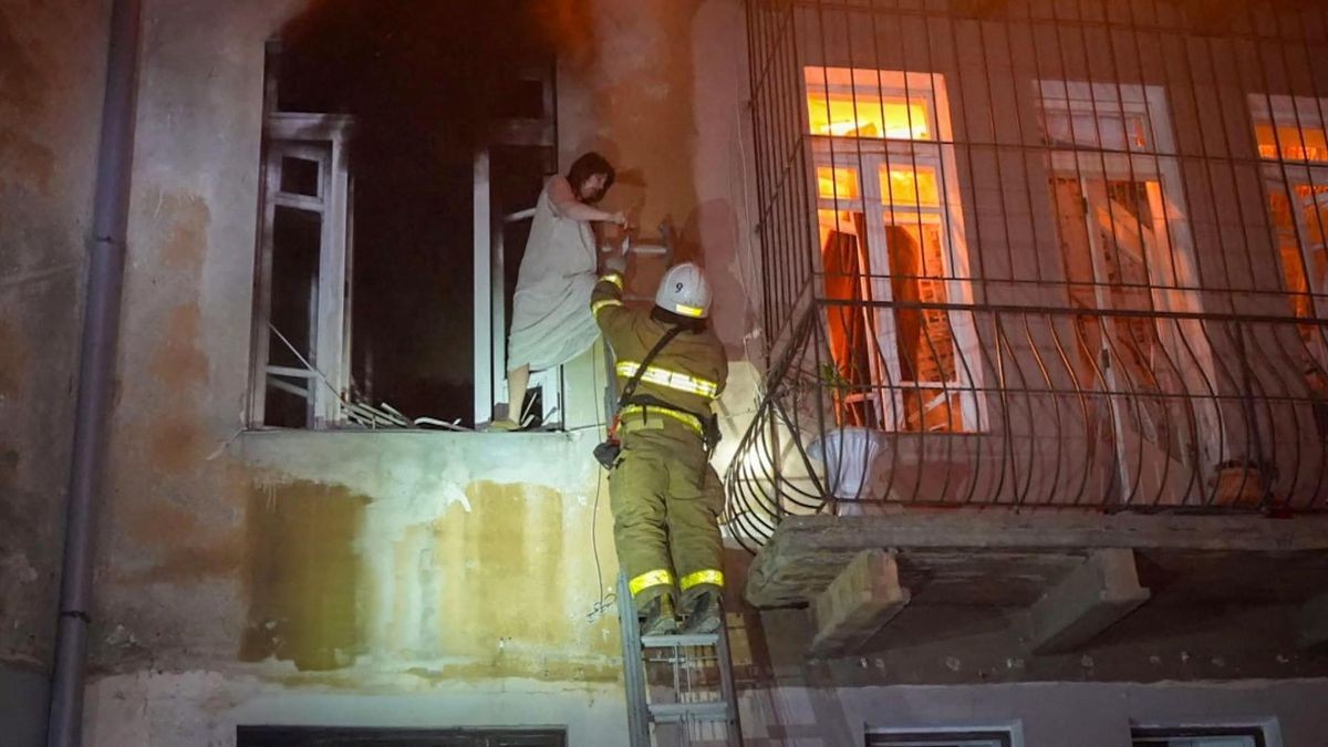 Eine Rettungskraft hilft einer Frau in Odessa aus einem brennenden Haus zu entkommen. Es wurde zum Ziel eines russischen Drohnenangriffs.
