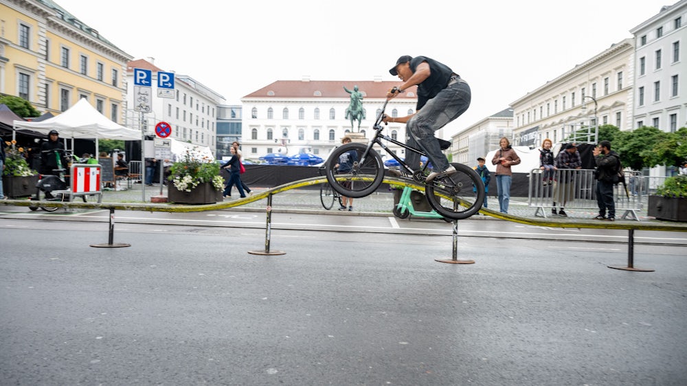 Einige BMX-Fahrer zeigen auf der Brienner Straße ihr Können, weil die aufgebaute Rampe wegen des Regens immer wieder abgedeckt wird.