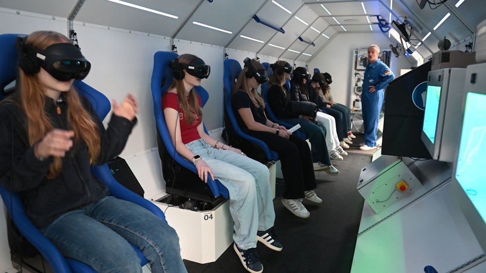 Auf beweglichen Sitzen und mit VR-Brillen wird ein Flug in den Weltraum simuliert.