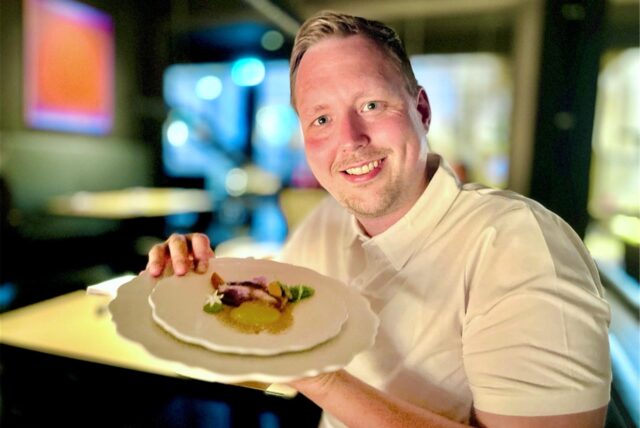 Ruhr-Nachrichten-Reporter Reporter Fabian Hollenhorst hält einen Teller aus dem Menü des Restaurants SchwarzGold in Dortmund in die Kamera.