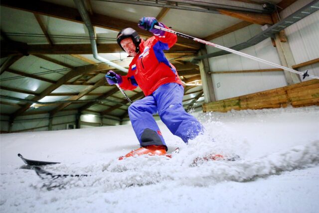 Ein Skifahrer fährt in einer Skihalle auf Kunstschnee.