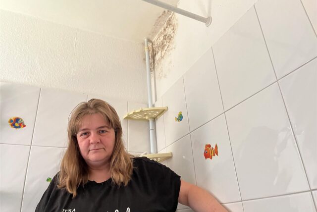 Jennifer Erler steht in ihrem Badezimmer. Im Hintergrund ist ein großer Schimmelfleck zu erkennen.