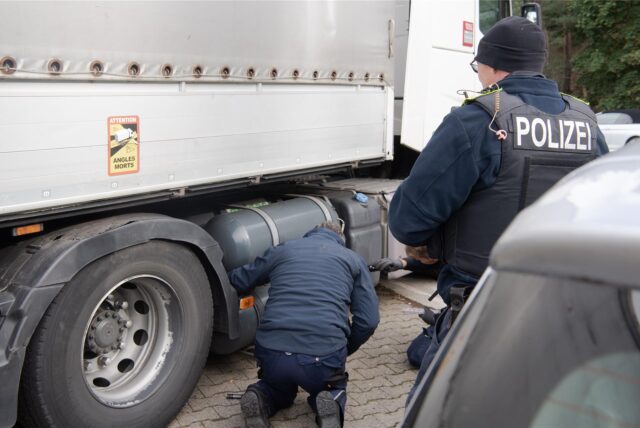 Polizeibeamte schaut sich bei einer Kontrolle von Schwerlastern auf dem Parkplatz Dreilinden die Erdgas-Tanks an einem Lkw an. (Symbolbild)