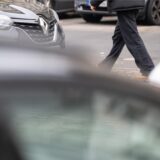Ein Fußgänger läuft zwischen parkenden Autos umher.