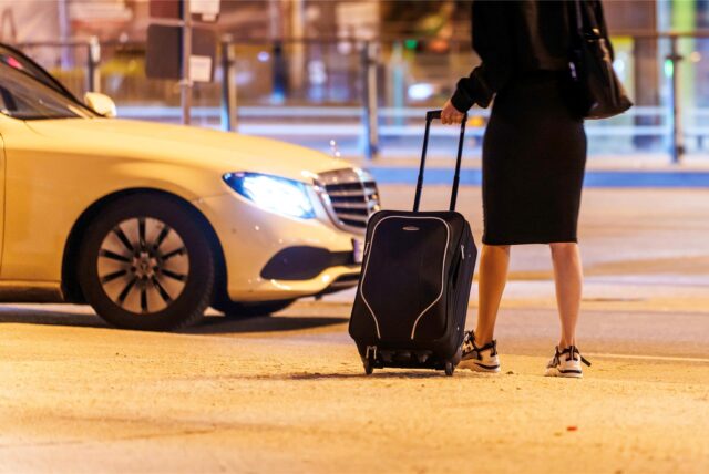 Eine Frau wartet abends nahe einem Hauptbahnhof auf ein Taxi.