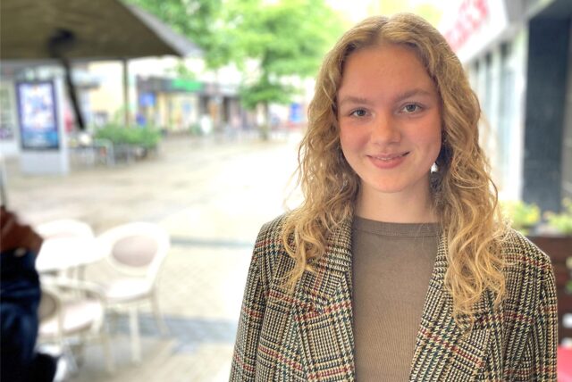 Cosima Caesar steht im Außenbereich des Cafés Feines in Dortmund-Hombruch. Sie lächelt in die Kamera.