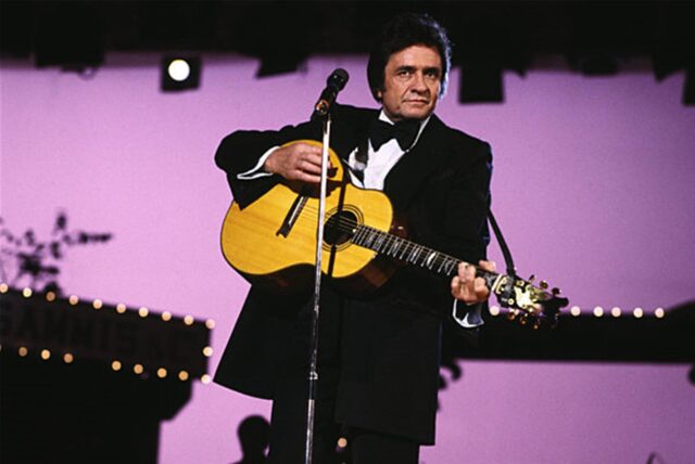 Johnny Cash mit einer Gitarre auf der Bühne.