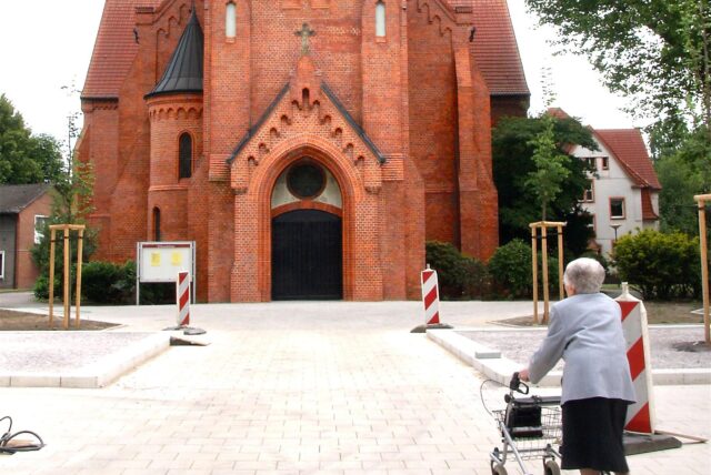 Eine Seniorin mit einem Rollator vor der Erlöserkirche in Herten.