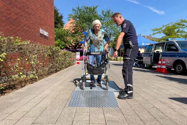 Polizeihauptkommissar Karsten Quante führt eine Seniorin mit einem Rollator durch einen Parcours.