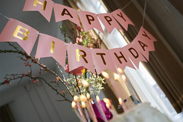 „Happy Birthday“ steht auf einer Girlande, die über einem Geburtstagstisch hängt.
