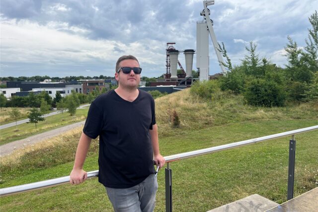 Mirco Veuhoff steht auf der Halde von Zeche Schlägel & Eisen, im Hintergrund der Förderturm.