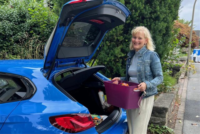 Cornelia Fröhlich steht mit einer Kiste neben einem blauen Auto. Sie betreibt eine Frühförderpraxis in Dortmund-Schönau.