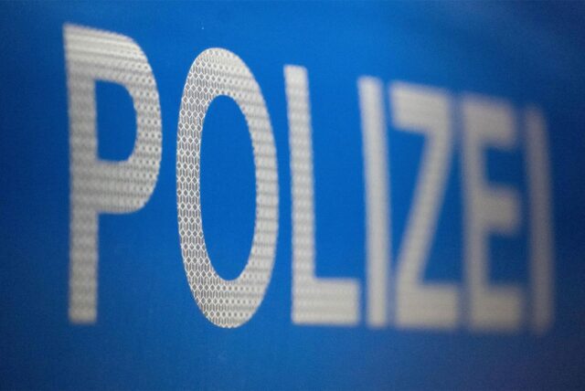 Nahaufnahme der teilweise unscharfen Aufschrift „POLIZEI“ in weiß auf blauem Grund. Die Buchstaben weisen eine reflektierende Wabenstruktur auf.