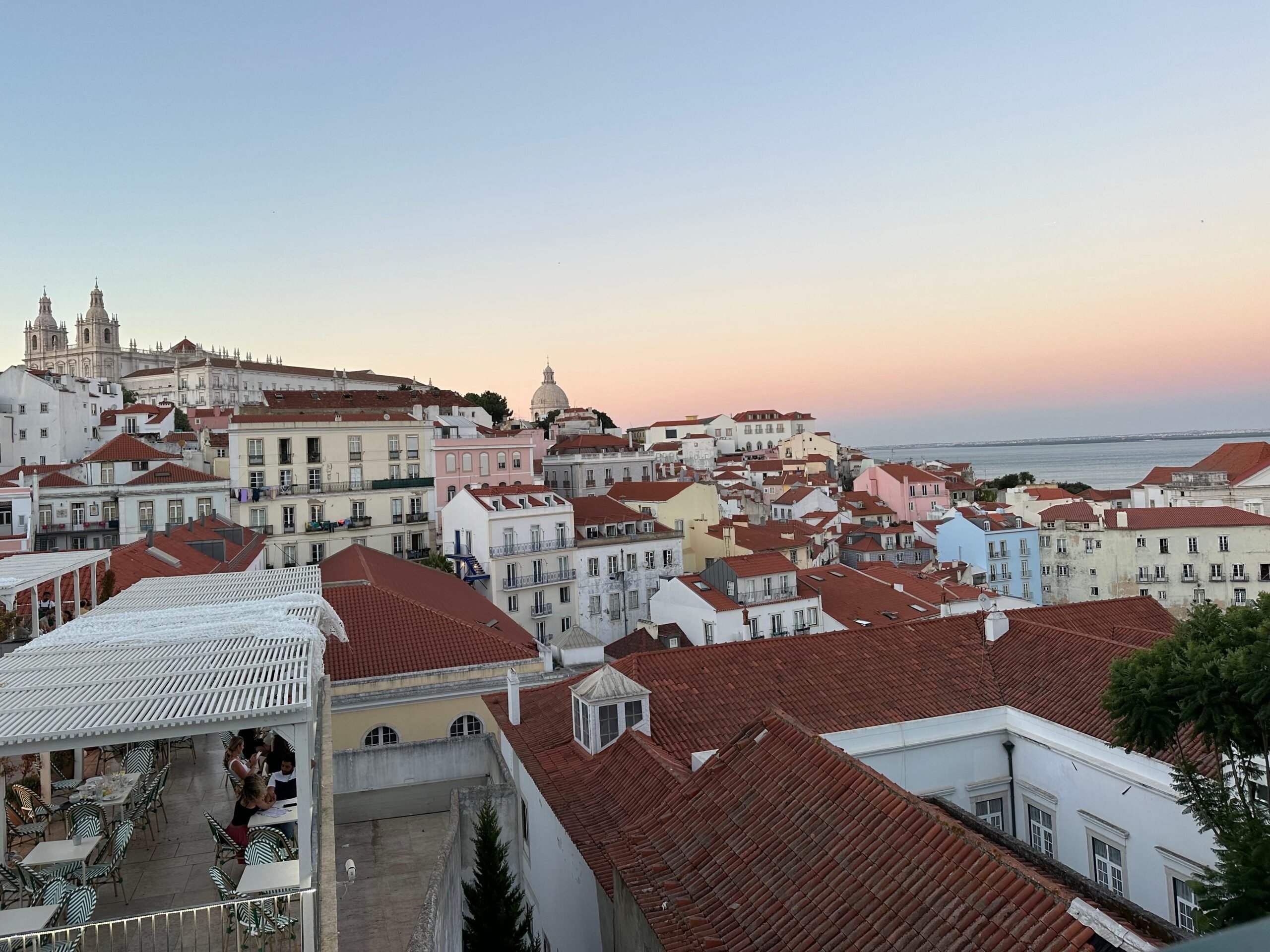 The sunset over red-roofed buildings in Lisbon.